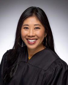 A woman poses for a photo in judge's robes.